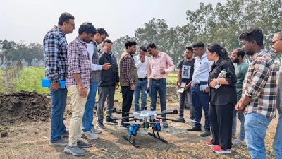 खेत में उपकरण के आसपास खड़े प्रशिक्षण प्रतिभागी